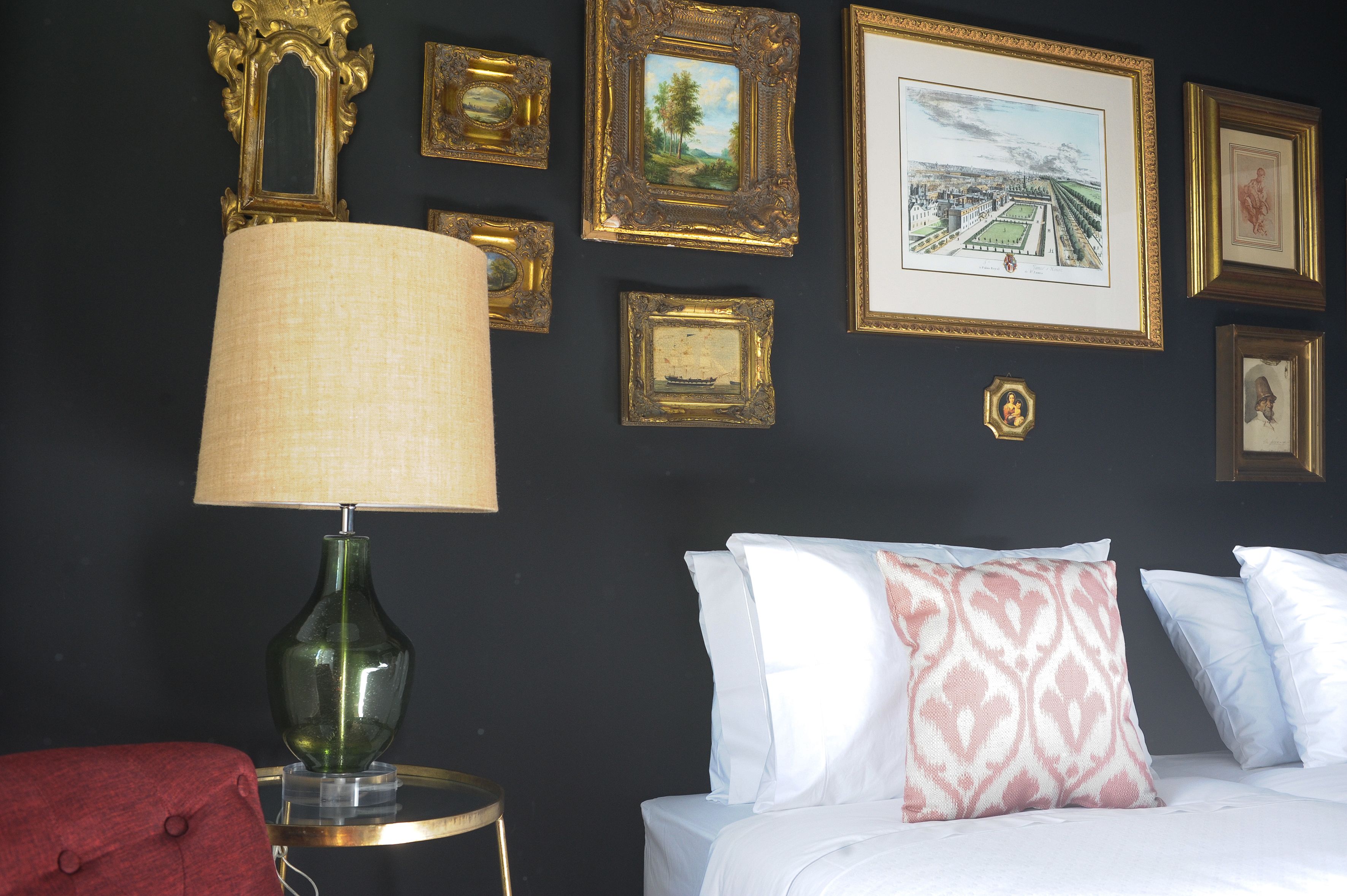 A room with a bed, a lamp, and framed pictures on the wall.