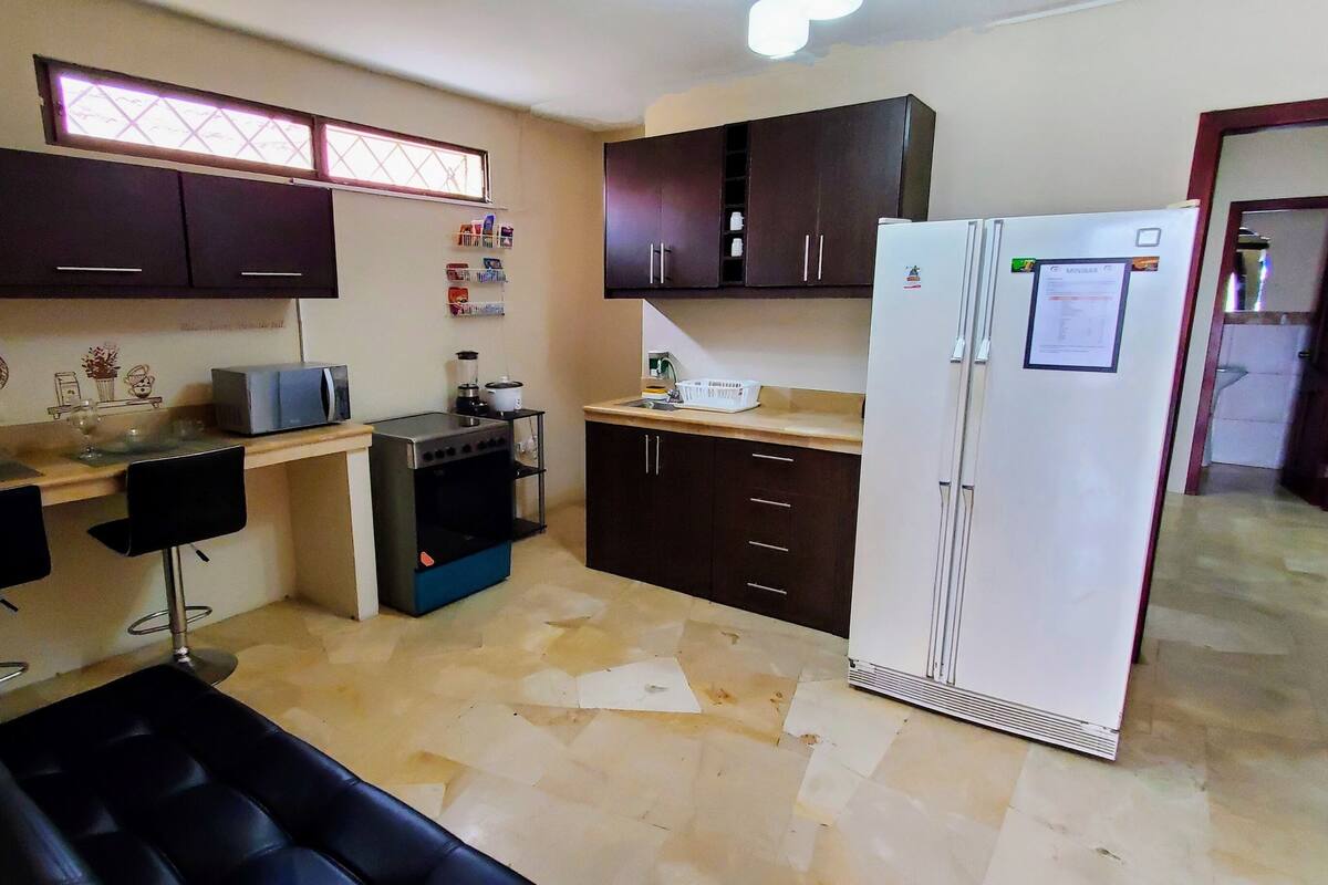 A compact kitchen with dark cabinets, a white refrigerator, a coffee maker, and a microwave.