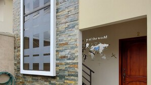 Ein modernes Gebäude mit einer Stein-Fassade, einem großen Fenster, einer Treppe und einer Tür mit Wandgemälde einer Weltkarte.