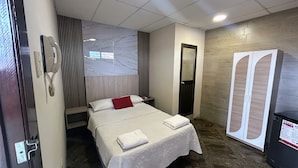 Ein Hotelzimmer mit Bett, Nachttisch, Spiegel, Kleiderschrank und Telefon.