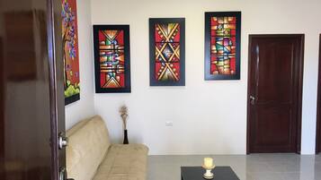 Una habitación con un sofá beige, una mesita con una vela y tres obras de arte enmarcadas en la pared.