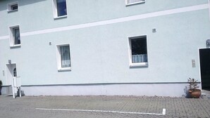 Un bâtiment à la façade bleu clair, doté de nombreuses fenêtres et d’un espace d’entrée pavé.
