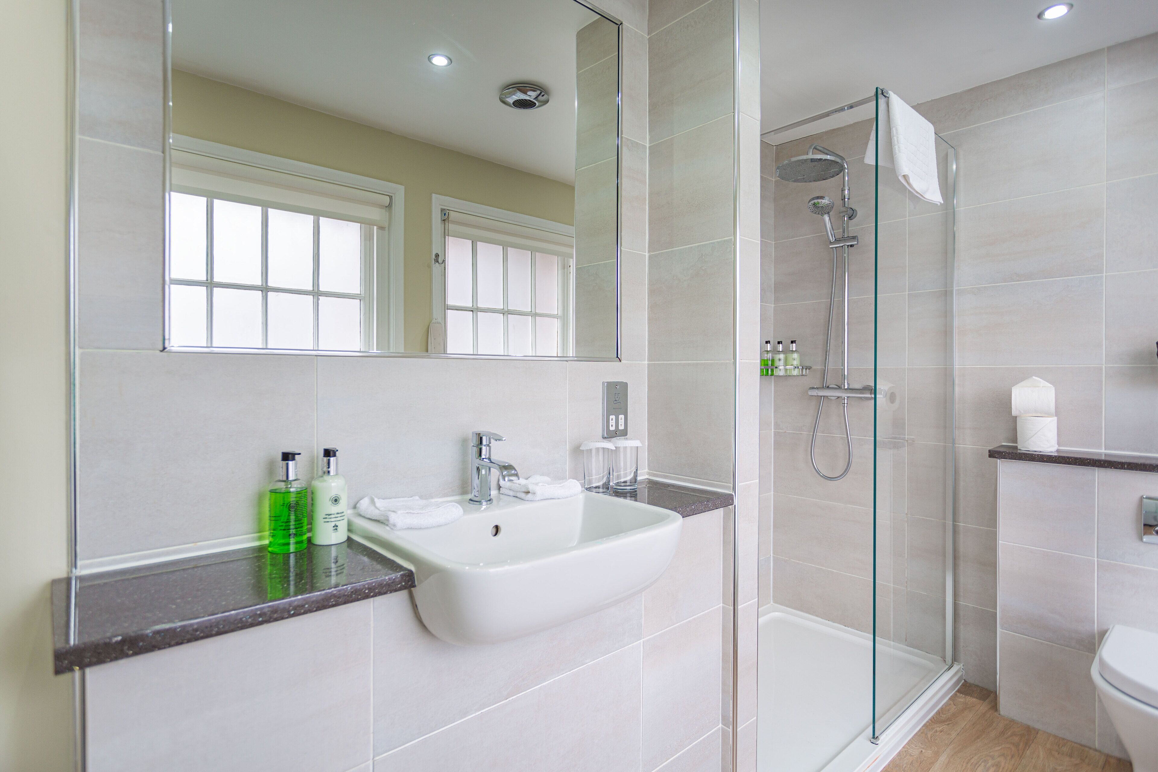 A modern bathroom with a glass-enclosed shower, a white sink, and a large mirror.