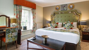 A well-appointed hotel room with a large bed, a desk with a chair, a window with curtains, and a nightstand with a lamp. - Wynnstay Hotel, Oswestry, Shropshire (Oswestry)