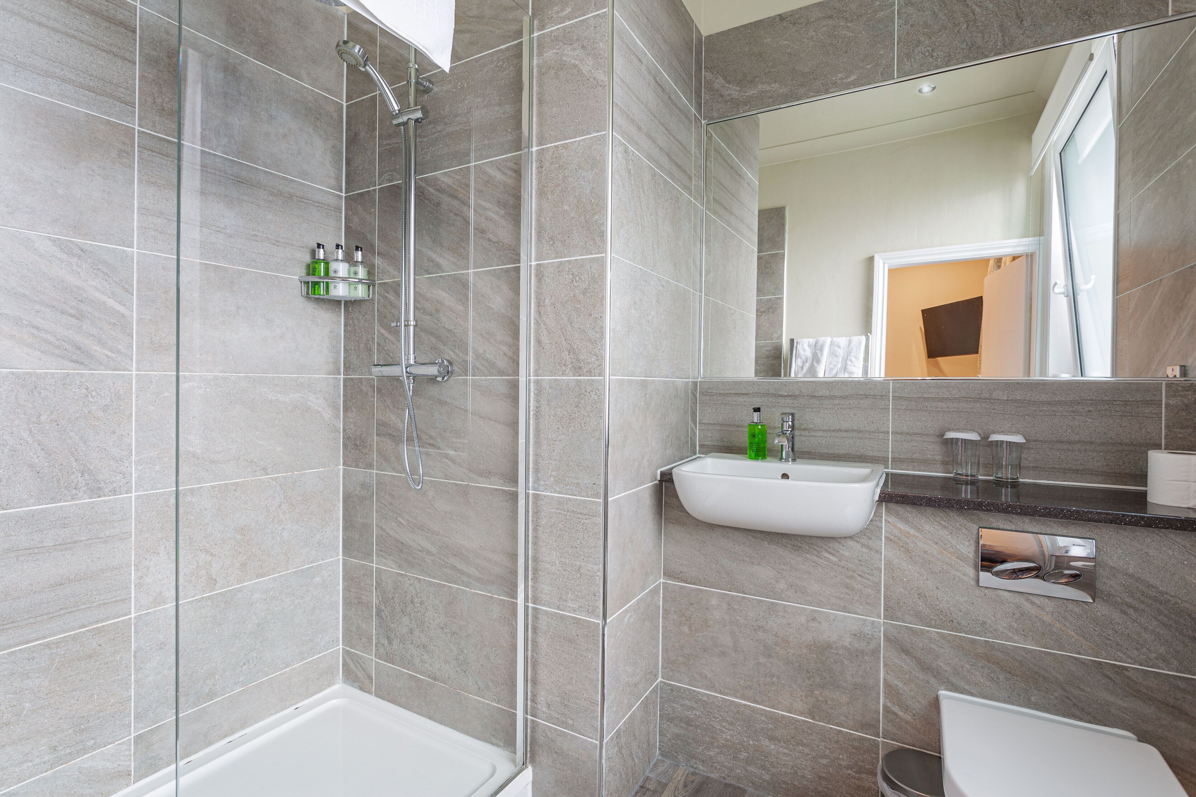 Un baño moderno con ducha, lavamanos e inodoro.