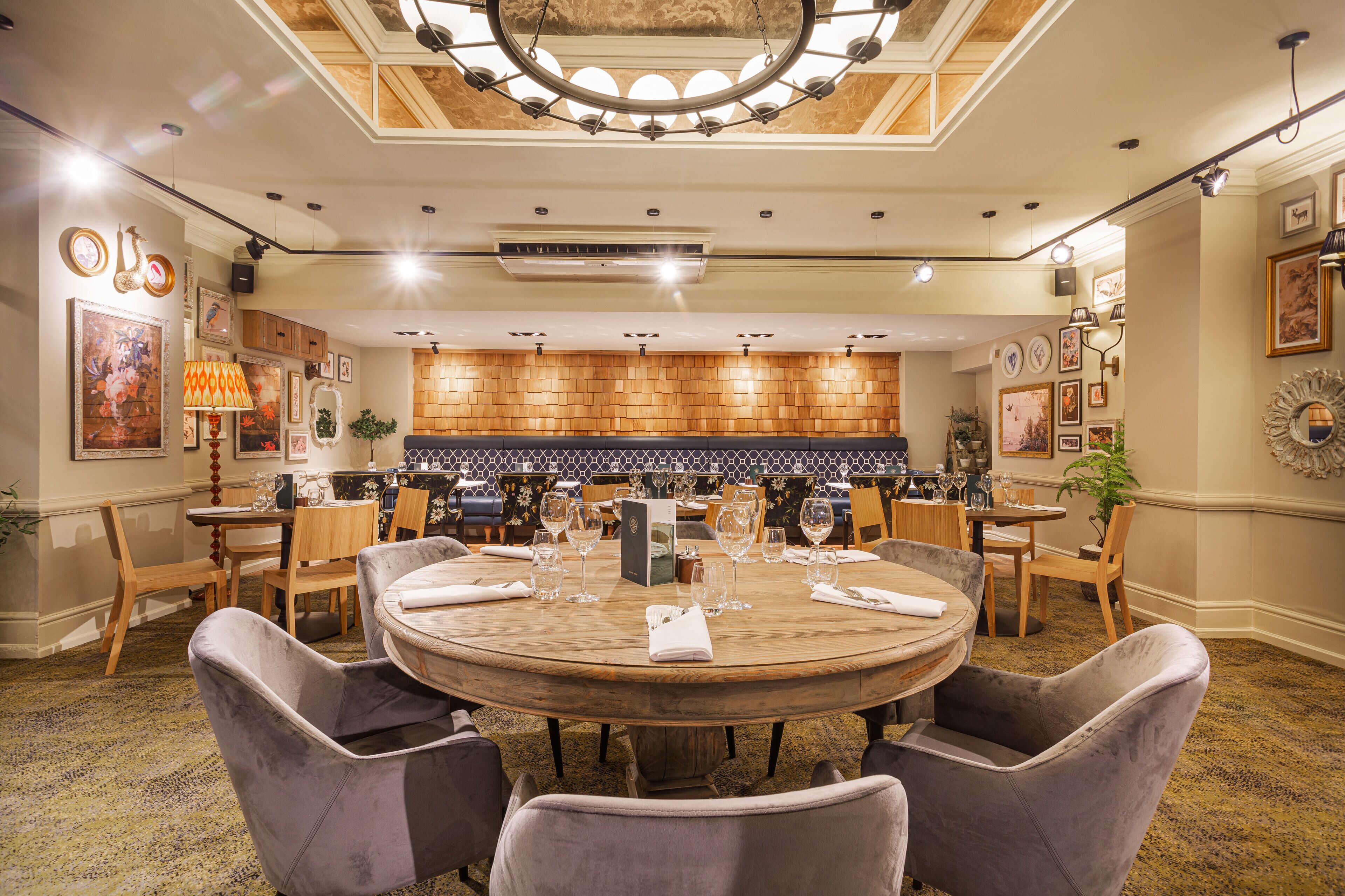 Un comedor amplio con una mesa de madera redonda, sillas tapizadas y un techo decorativo.