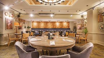 Un comedor amplio con una mesa de madera redonda, sillas tapizadas y un techo decorativo.