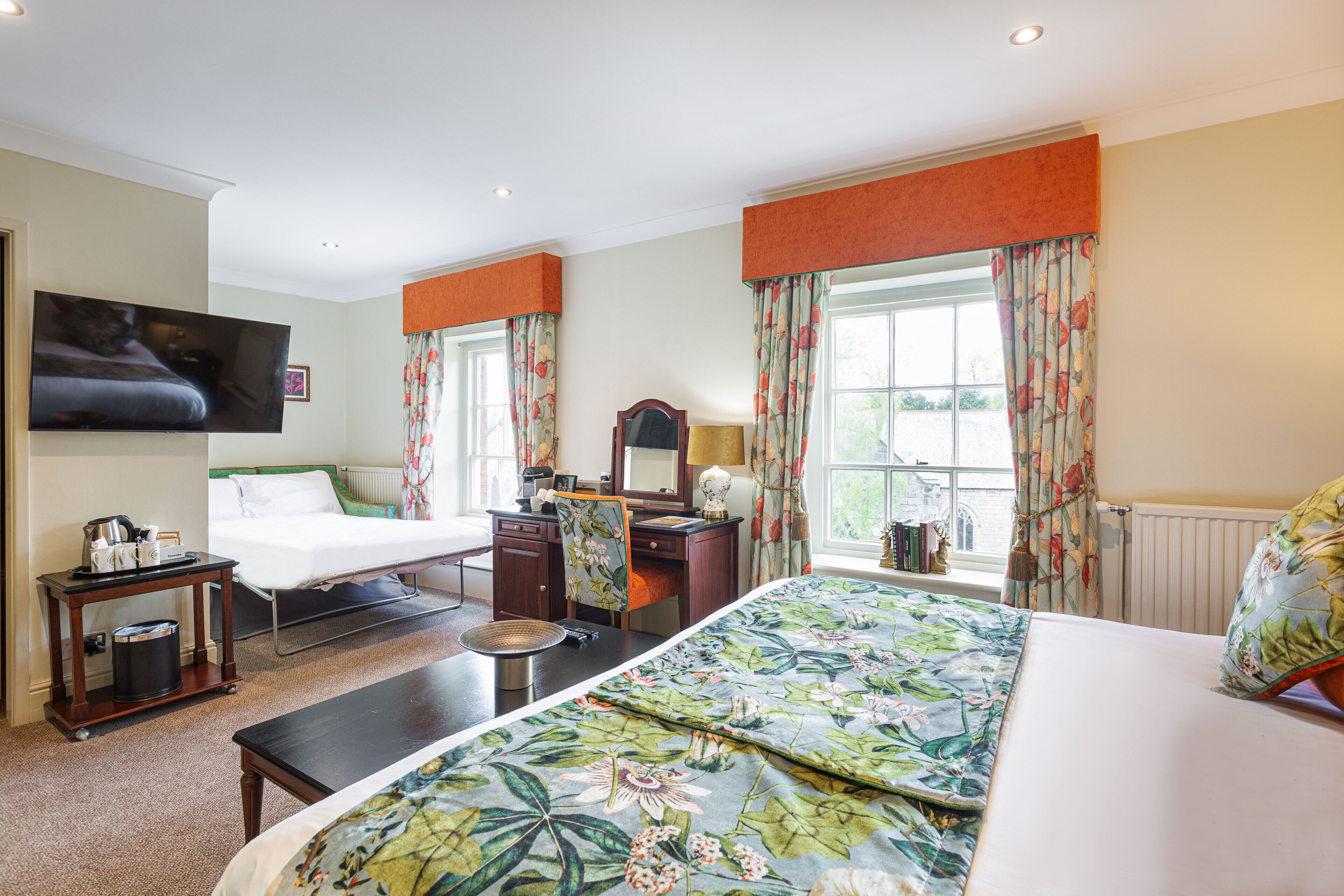Une chambre d’hôtel équipée d’un lit, d’un bureau, d’une chaise, d’une télévision et d’une fenêtre avec des rideaux.