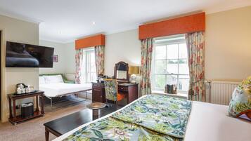 Une chambre d’hôtel équipée d’un lit, d’un bureau, d’une chaise, d’une télévision et d’une fenêtre avec des rideaux.