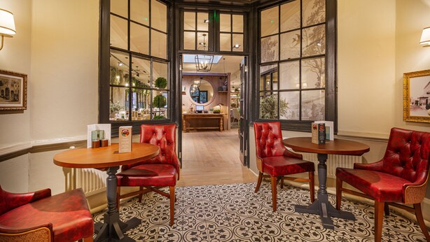 A restaurant with red leather chairs and tables, large windows, and a patterned floor. - Wynnstay Hotel, Oswestry, Shropshire (Oswestry)