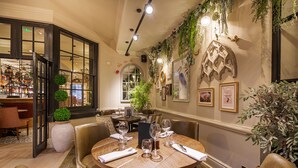 A dining area with round tables, chairs, and a bar with shelves of bottles. - Wynnstay Hotel, Oswestry, Shropshire (Oswestry)