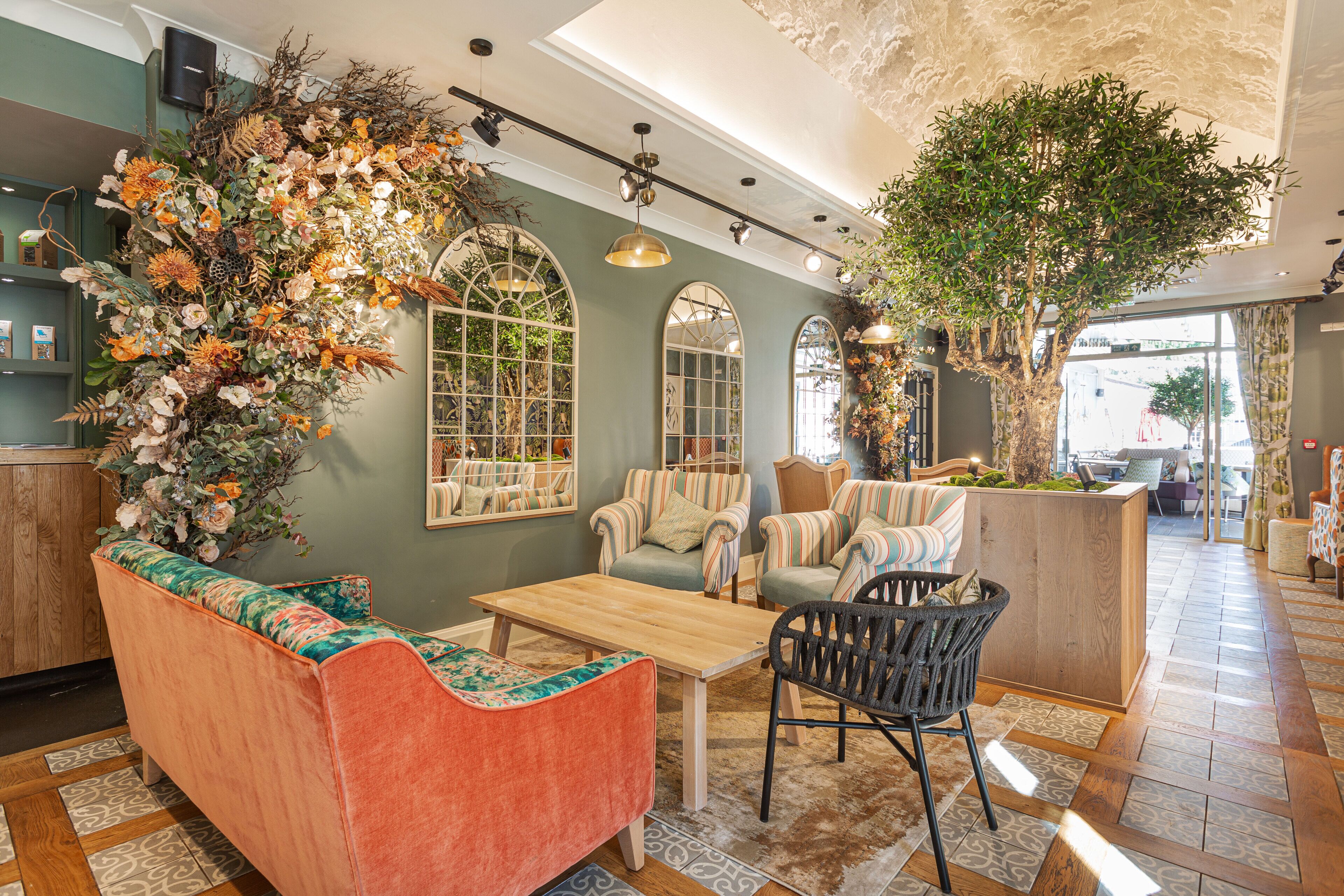 Un rincón acogedor con un sofá, sillas, una mesa de centro de madera y un arreglo decorativo de plantas.