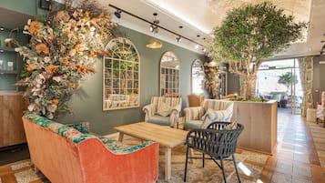 Un rincón acogedor con un sofá, sillas, una mesa de centro de madera y un arreglo decorativo de plantas.