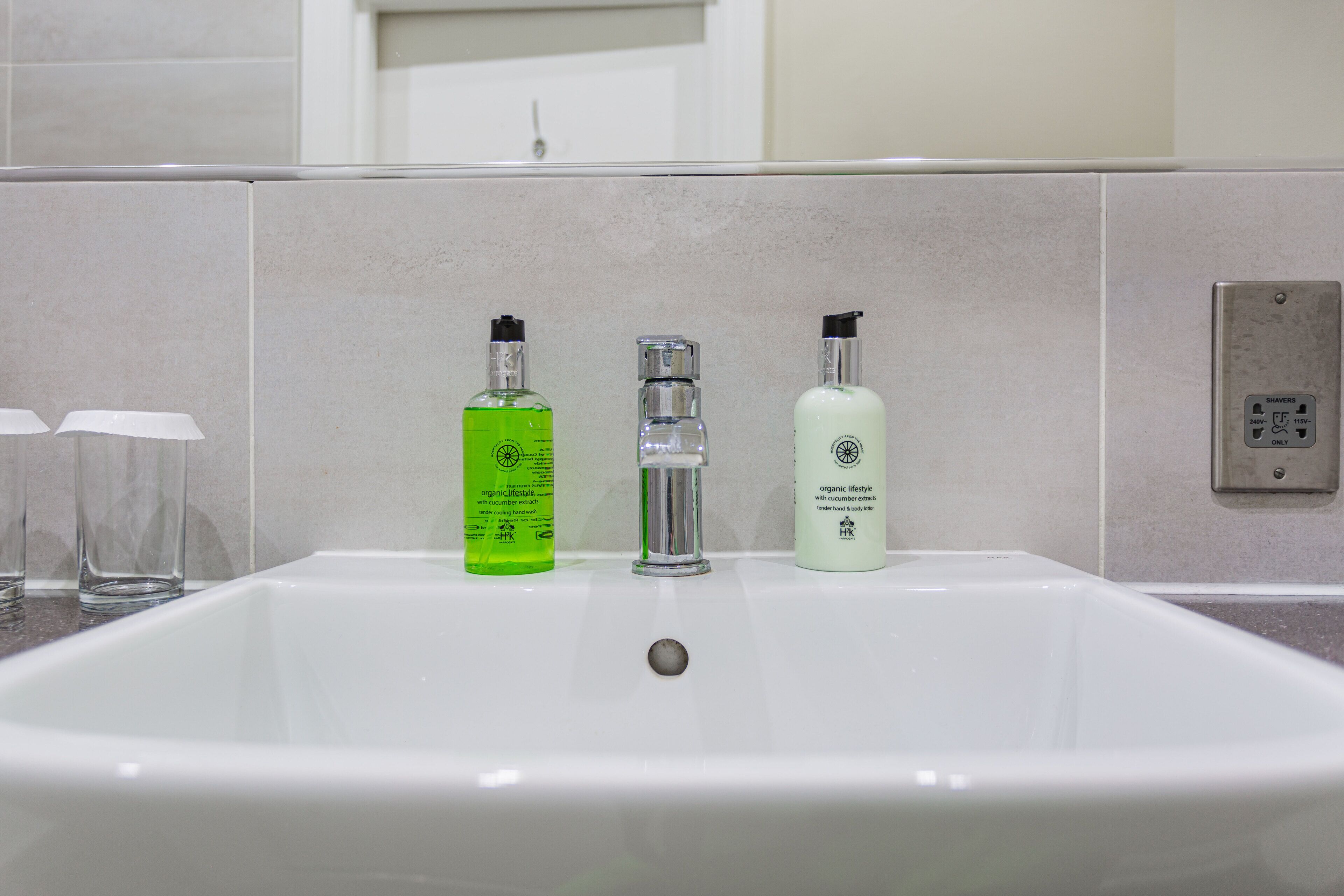 A bathroom sink with three bottles of liquid soap and a faucet.