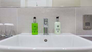A bathroom sink with three bottles of liquid soap and a faucet.