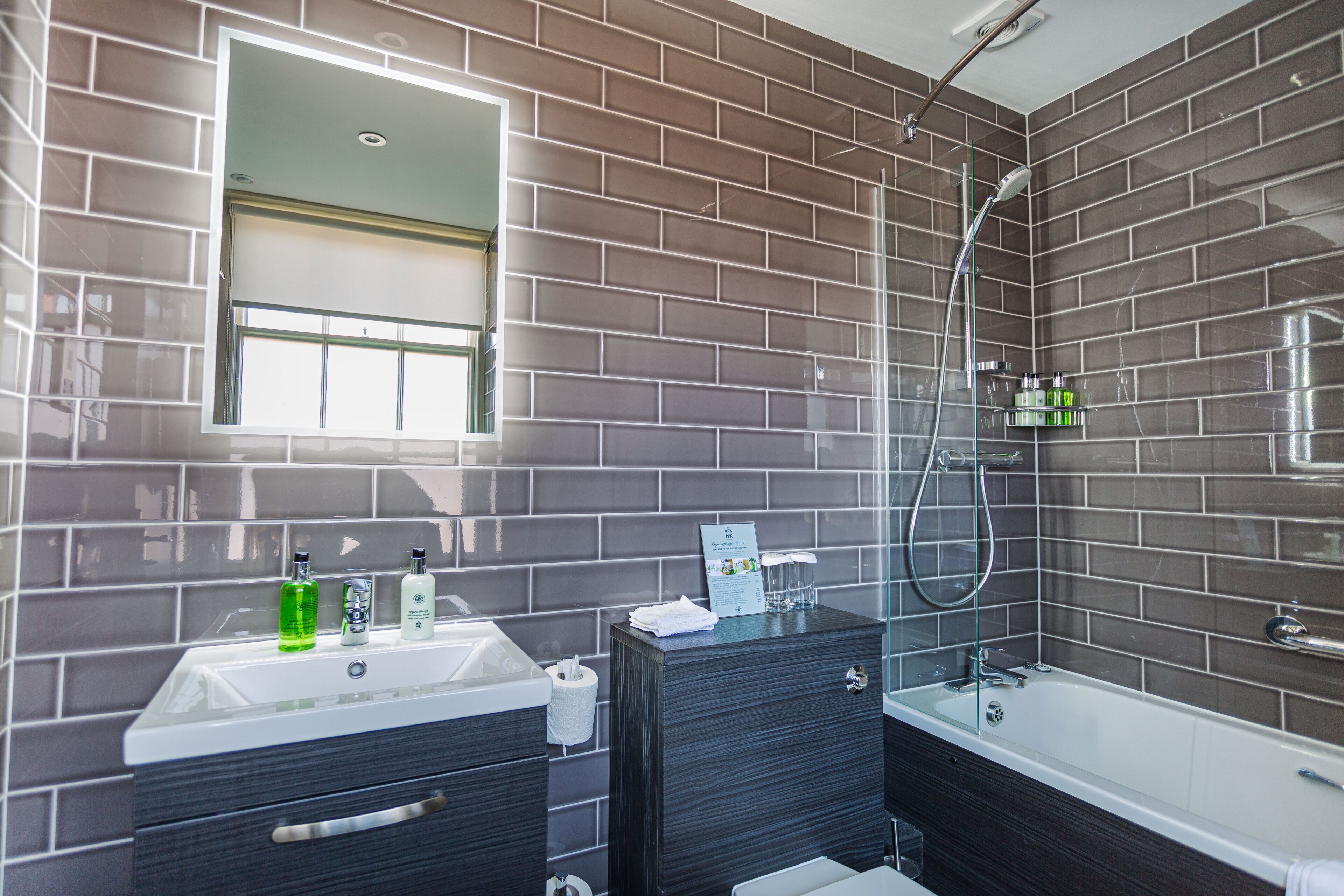 Une salle de bain moderne avec un grand miroir, une baignoire et un espace douche.