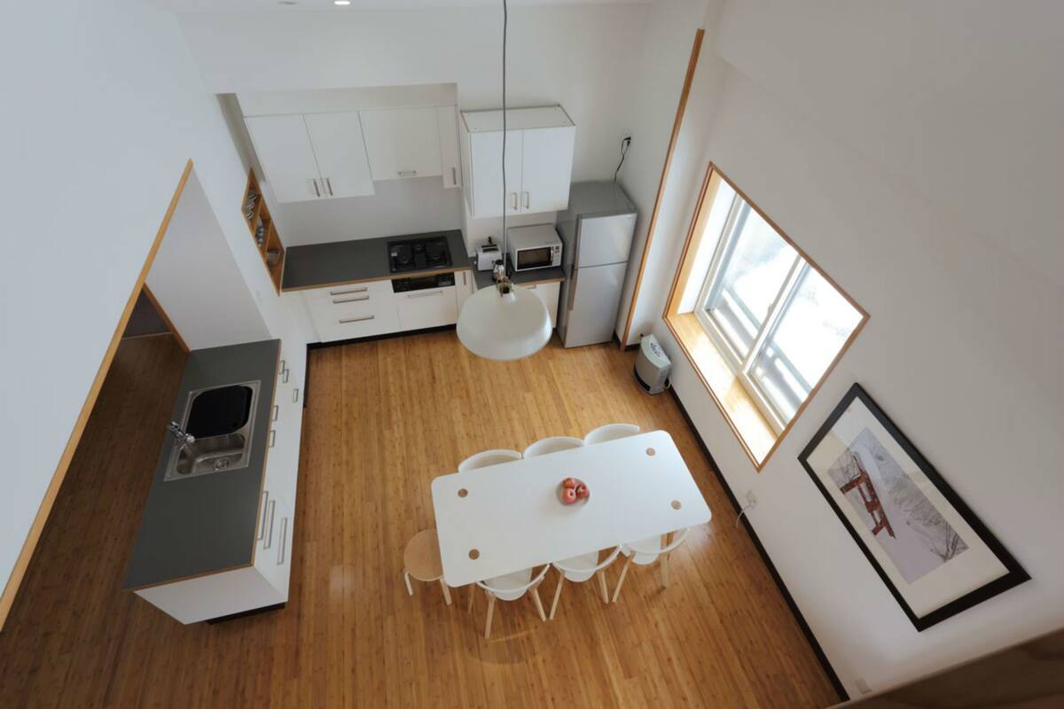 Une cuisine compacte avec des meubles blancs, une table à manger avec des chaises, un four à micro-ondes et un évier.