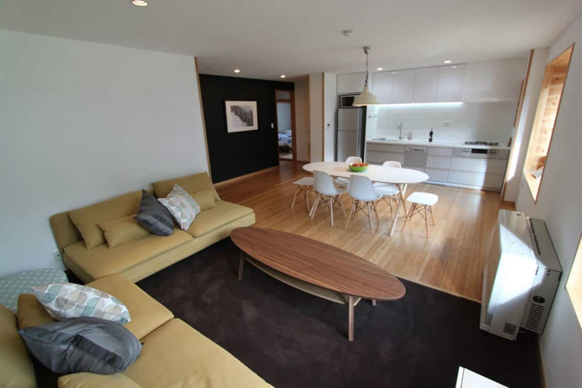 Un salon moderne comprenant un canapé, une table basse et un coin repas avec des chaises et une table.