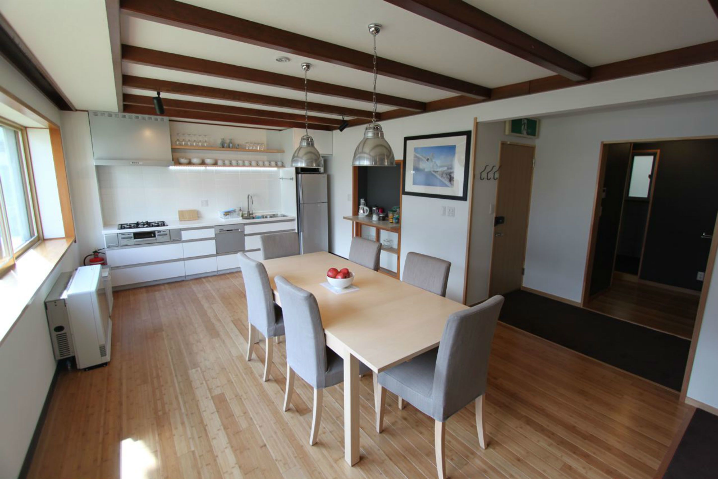 Una cocina moderna con comedor, vigas de madera en el techo y un amplio ventanal que proporciona luz natural.