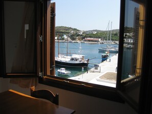 Vista desde una habitación con ventana que da a un puerto deportivo con barcos, un muelle y edificios al fondo.