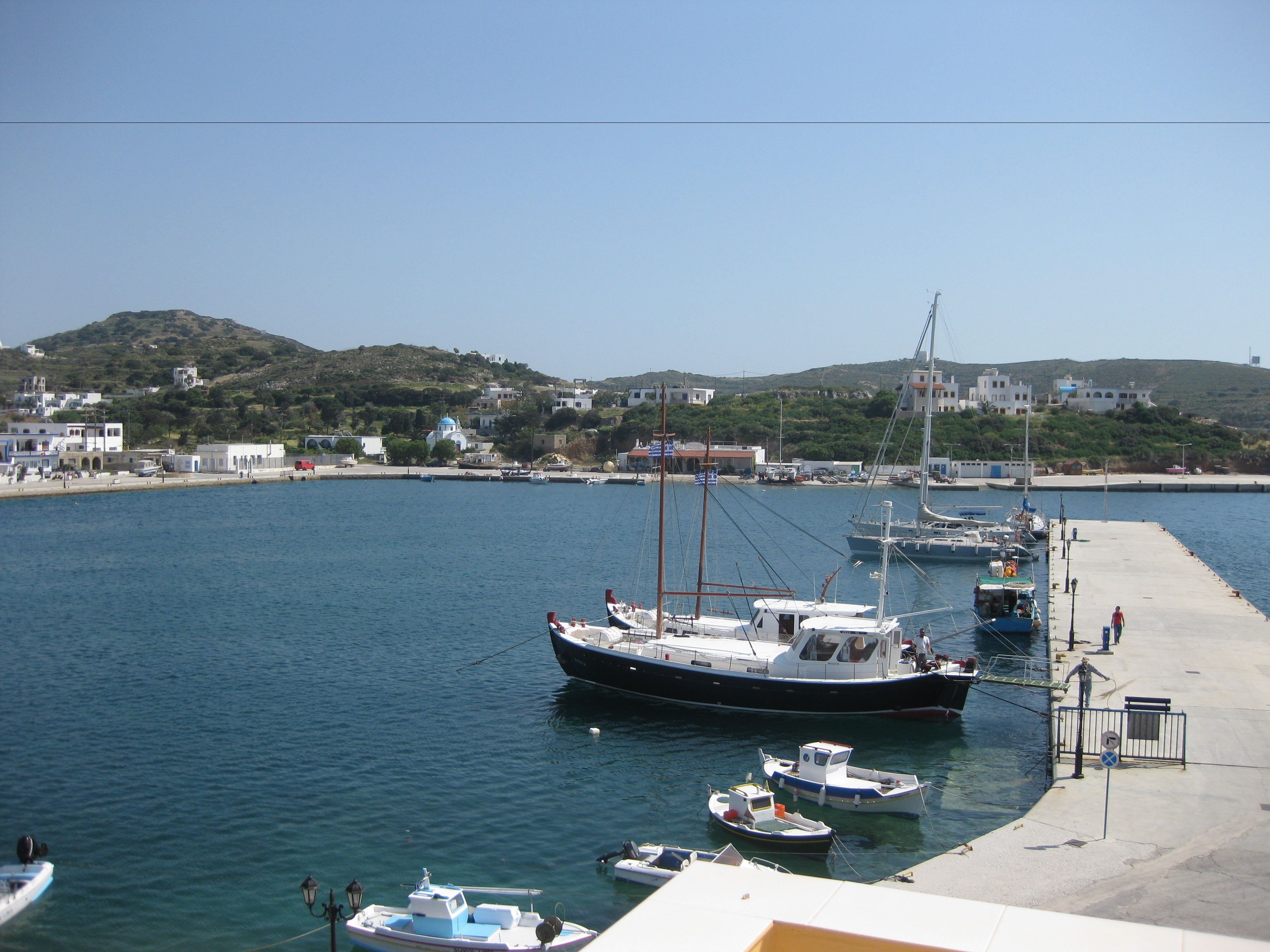 Una marina con varios barcos amarrados, un muelle y edificios al fondo.