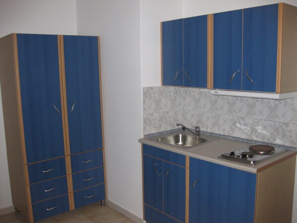 Une cuisine avec des meubles de couleur bleue, un évier en acier inoxydable et une cuisinière à gaz.
