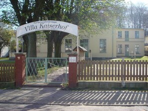 A gated entrance to Villa Kaiserhof, a residential property with a brick gate and a sign above it. - Villa Kaiserhof (Zinnowitz)