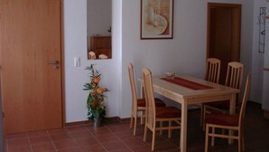 A dining area with a wooden table and chairs, a vase of flowers, and a framed picture on the wall. - Villa Kaiserhof (Zinnowitz)