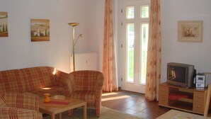 A living room with a sofa, chairs, a television, and a radiator. - Villa Kaiserhof (Zinnowitz)