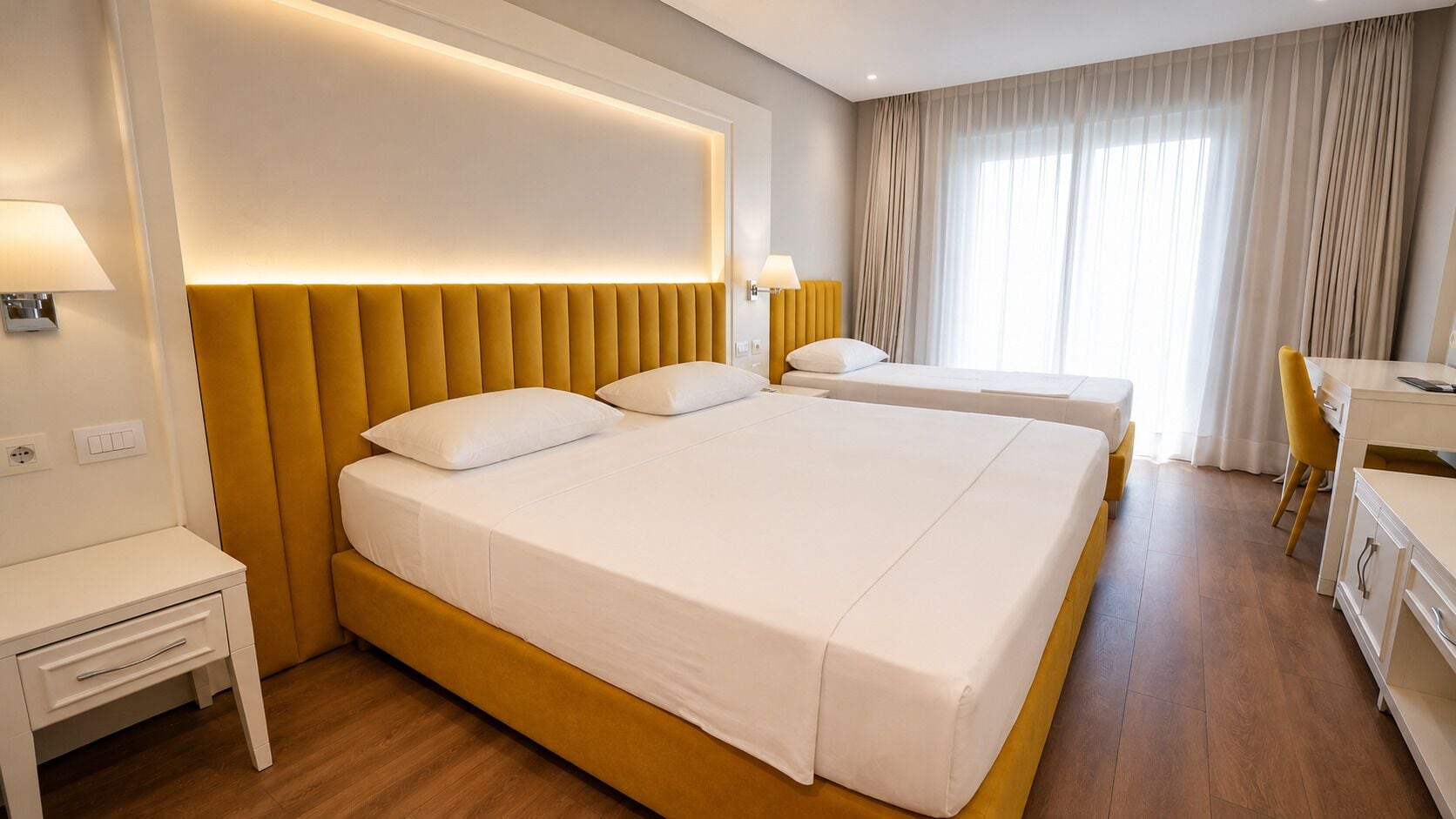 A hotel room with a large bed, bedside tables, a desk, and a chair.
