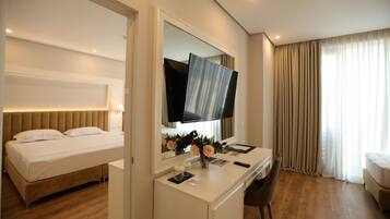 Une chambre d’hôtel avec un lit, un bureau et une chaise, une télévision et une grande fenêtre avec des rideaux.