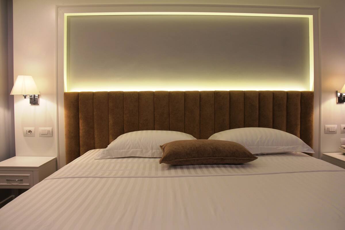 A hotel room with a large bed, two bedside lamps, and a modern headboard.
