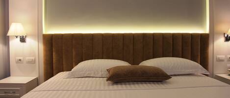 A hotel room with a large bed, two bedside lamps, and a modern headboard.