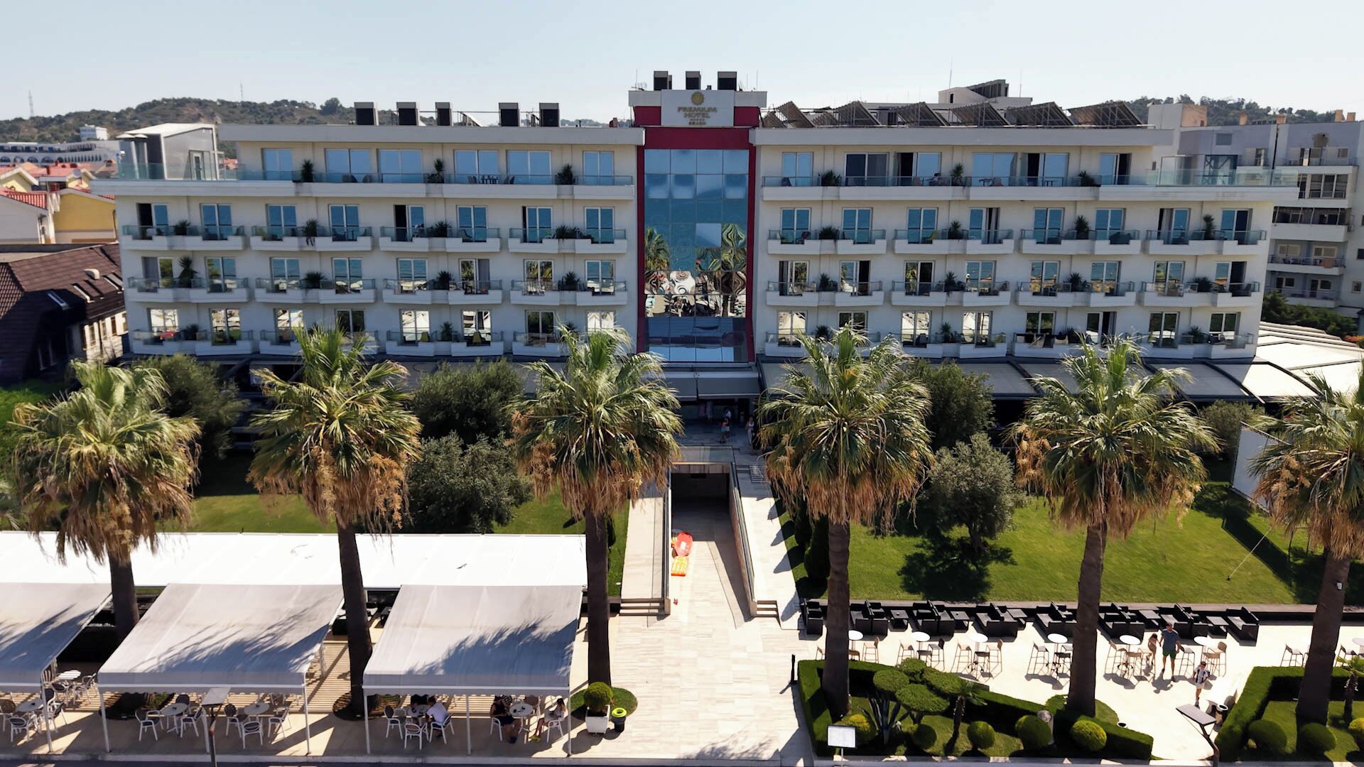 Un hôtel à étages, doté d’une terrasse et bordé de palmiers.