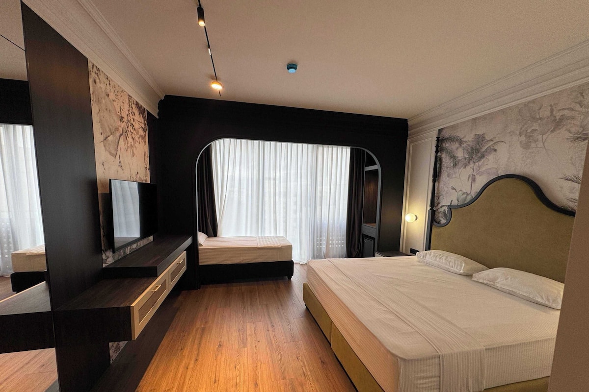 A hotel room with a bed, a TV, a desk, and a mirror.