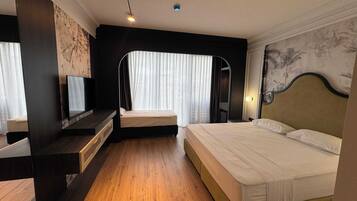 Et hotelværelse med seng, fjernsyn, skrivebord og spejl.