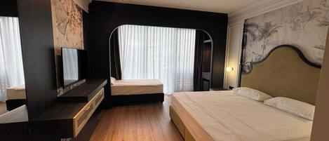 A hotel room with a bed, a TV, a desk, and a mirror.