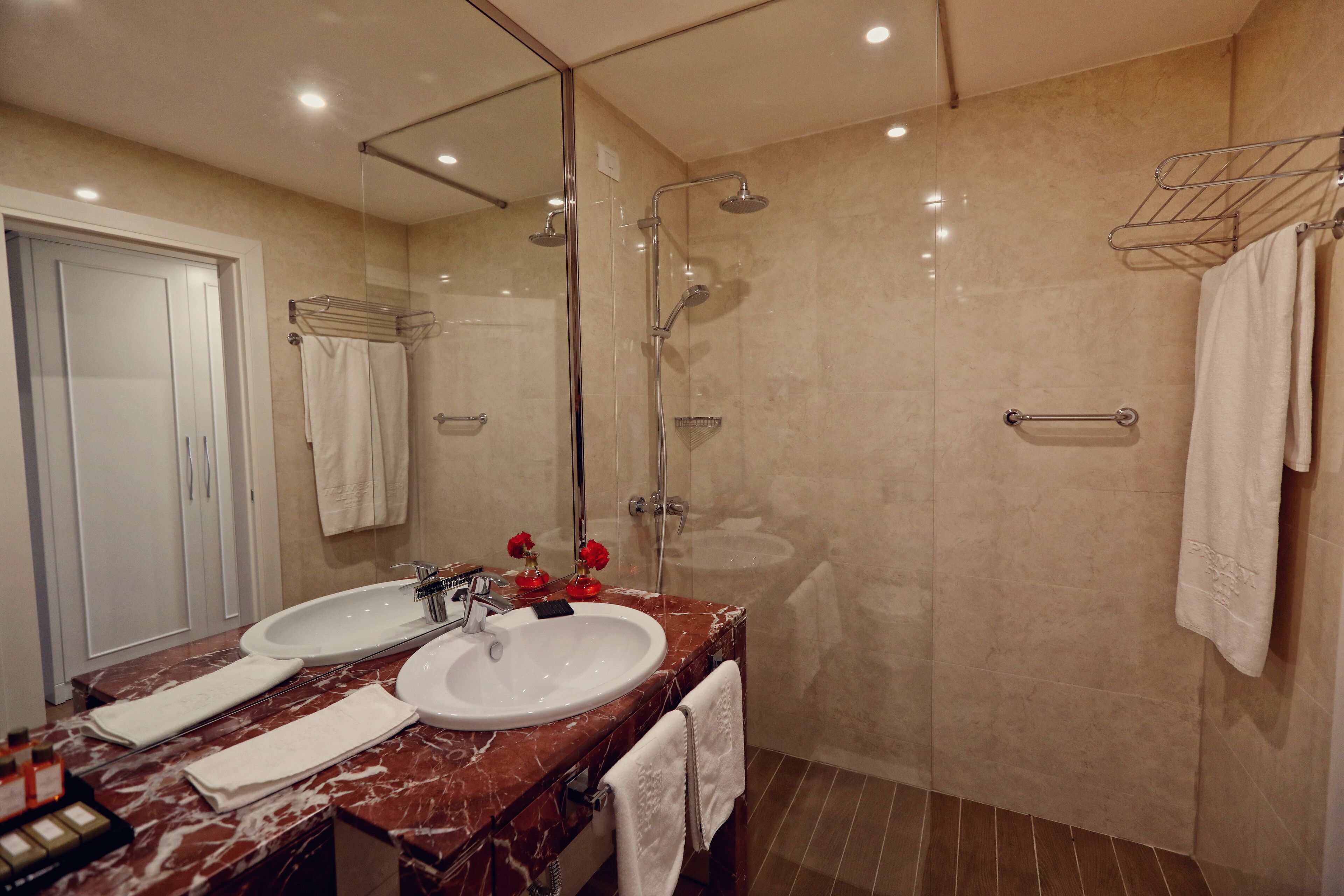 Une salle de bain moderne avec deux vasques, une douche à l’italienne en verre et un meuble-lavabo en marbre.