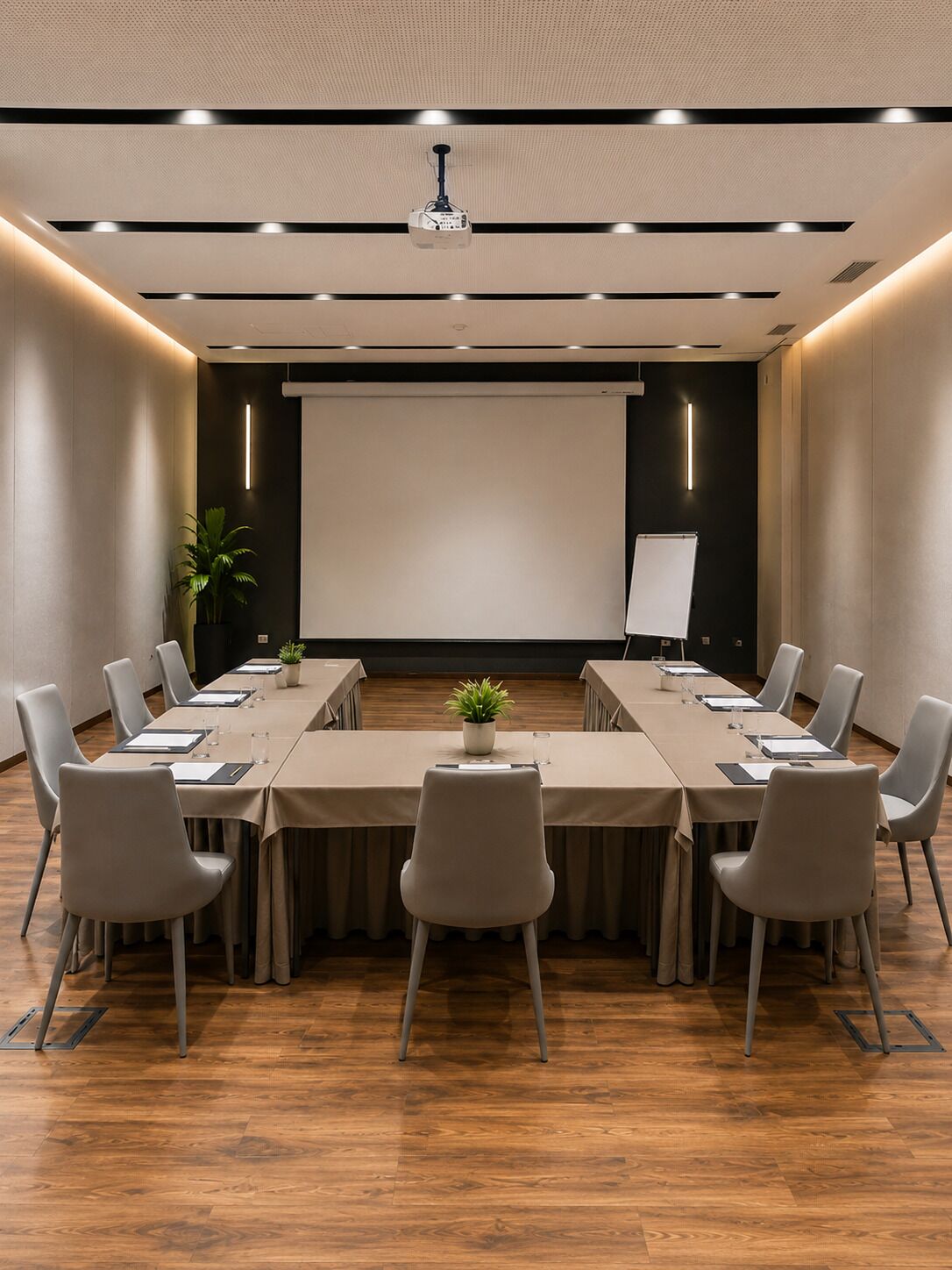 A conference room with a long table, chairs, a projector, and a screen.