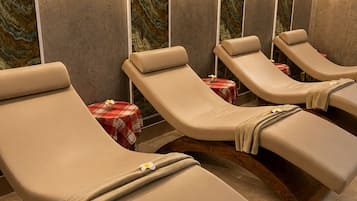 Um espaço de spa com várias poltronas reclináveis, iluminação embutida e um design de parede semelhante a mármore.