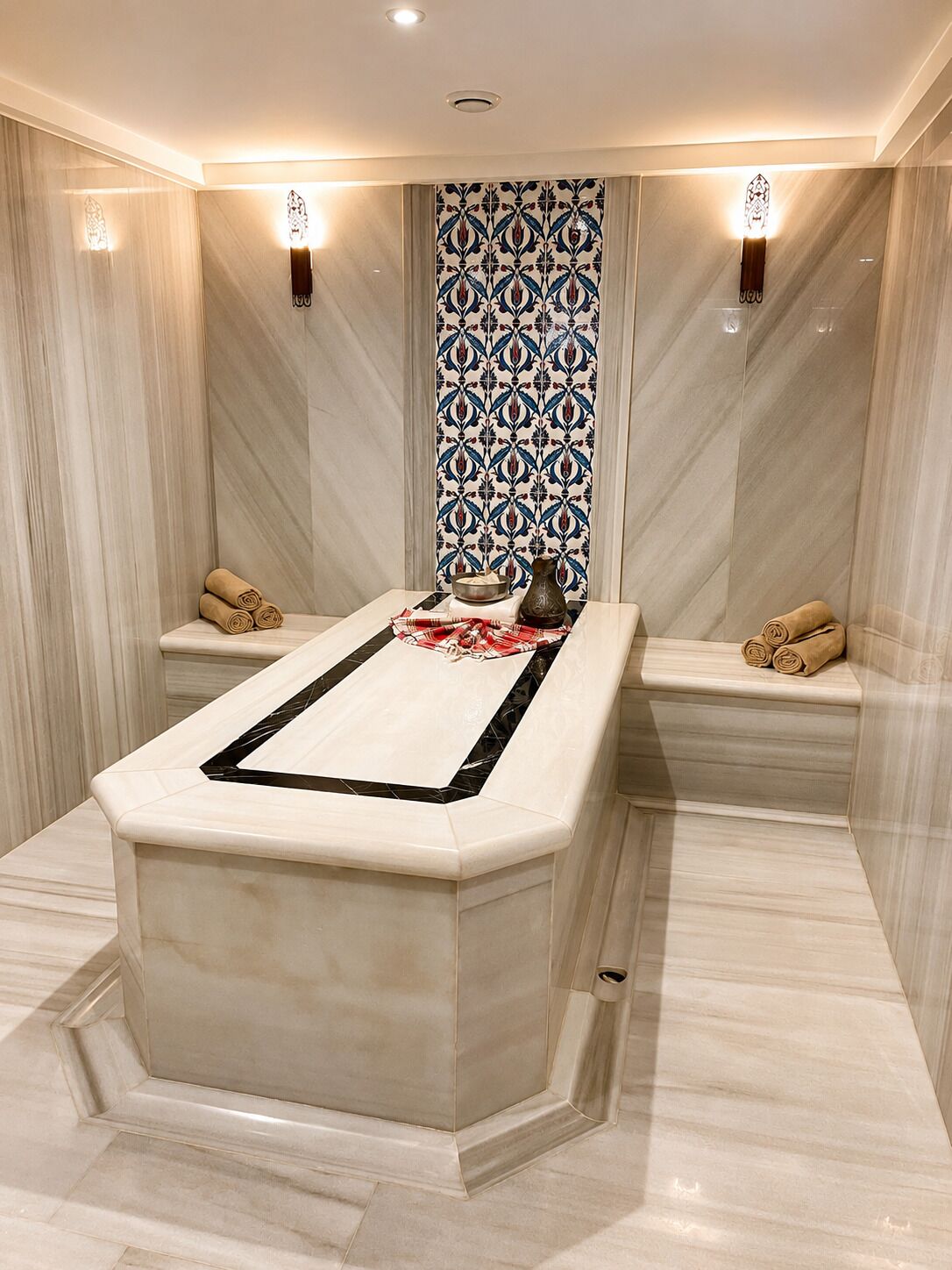 Ein modernes Badezimmer mit einem zentralen Marmorwaschbecken, zwei Handtuchhaltern und einer Wand mit Muster.