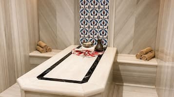 Ein modernes Badezimmer mit einem zentralen Marmorwaschbecken, zwei Handtuchhaltern und einer Wand mit Muster.