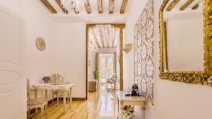 Un pasillo con suelo de madera, un comedor con mesa y sillas, y un espejo grande en la pared.