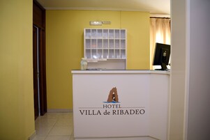 Una recepción en HOTEL VILLA de RIBADEO, con una vitrina decorativa y un monitor de ordenador.
