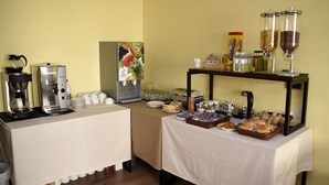 A buffet setup with a coffee station, fruit dispenser, and various food items on tables. - Hotel Villa De Ribadeo (Ribadeo)