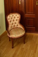 Una silla de madera con asiento y respaldo acolchados, ubicada frente a una puerta de madera con manija de latón.