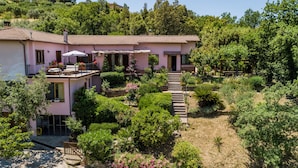 A two-story house with a balcony, surrounded by lush greenery and a garden. - Albachiara Casa Di Campagna B&B (Ogliastro Cilento)
