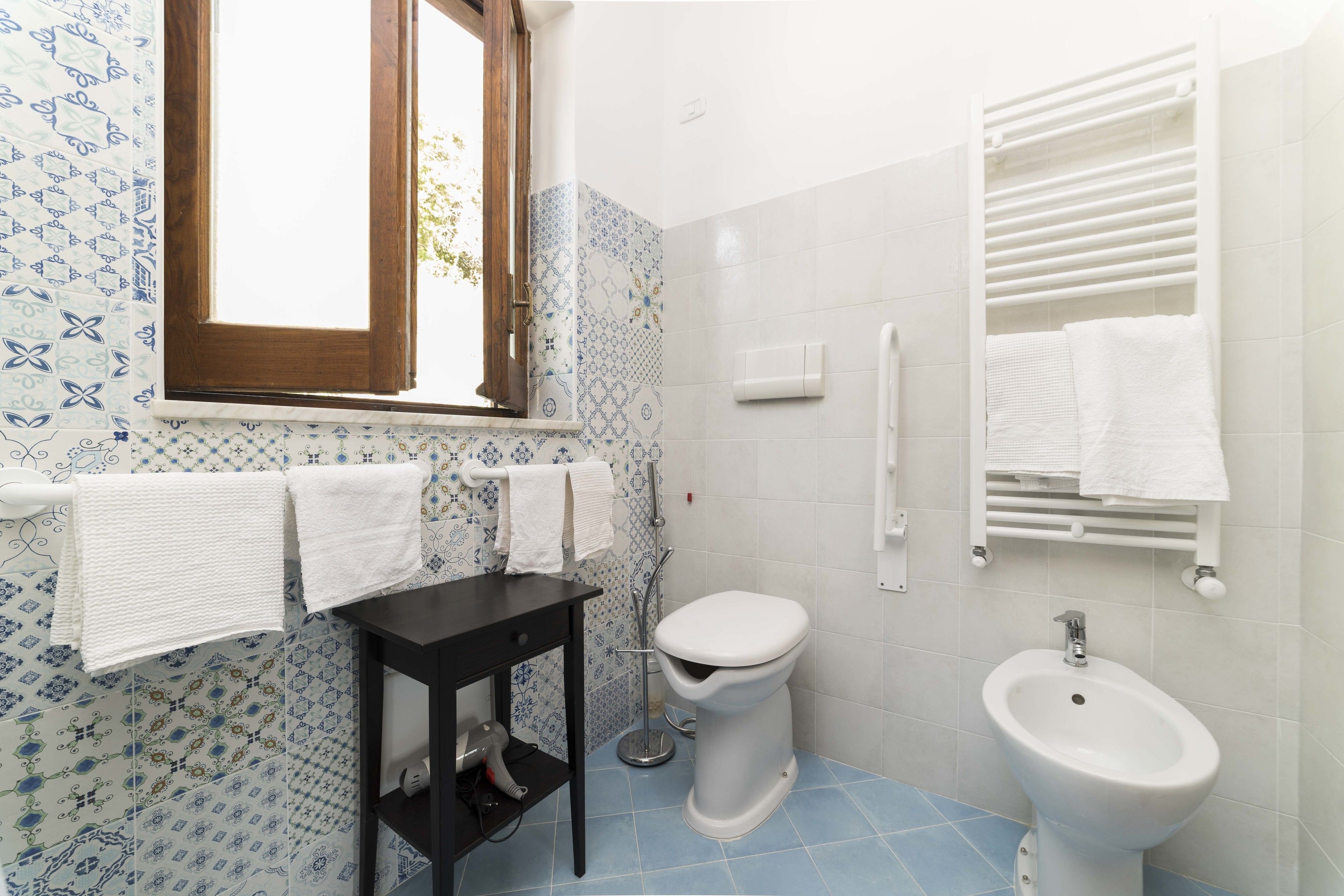 Un baño con inodoro, bidé y un perchero para toallas.