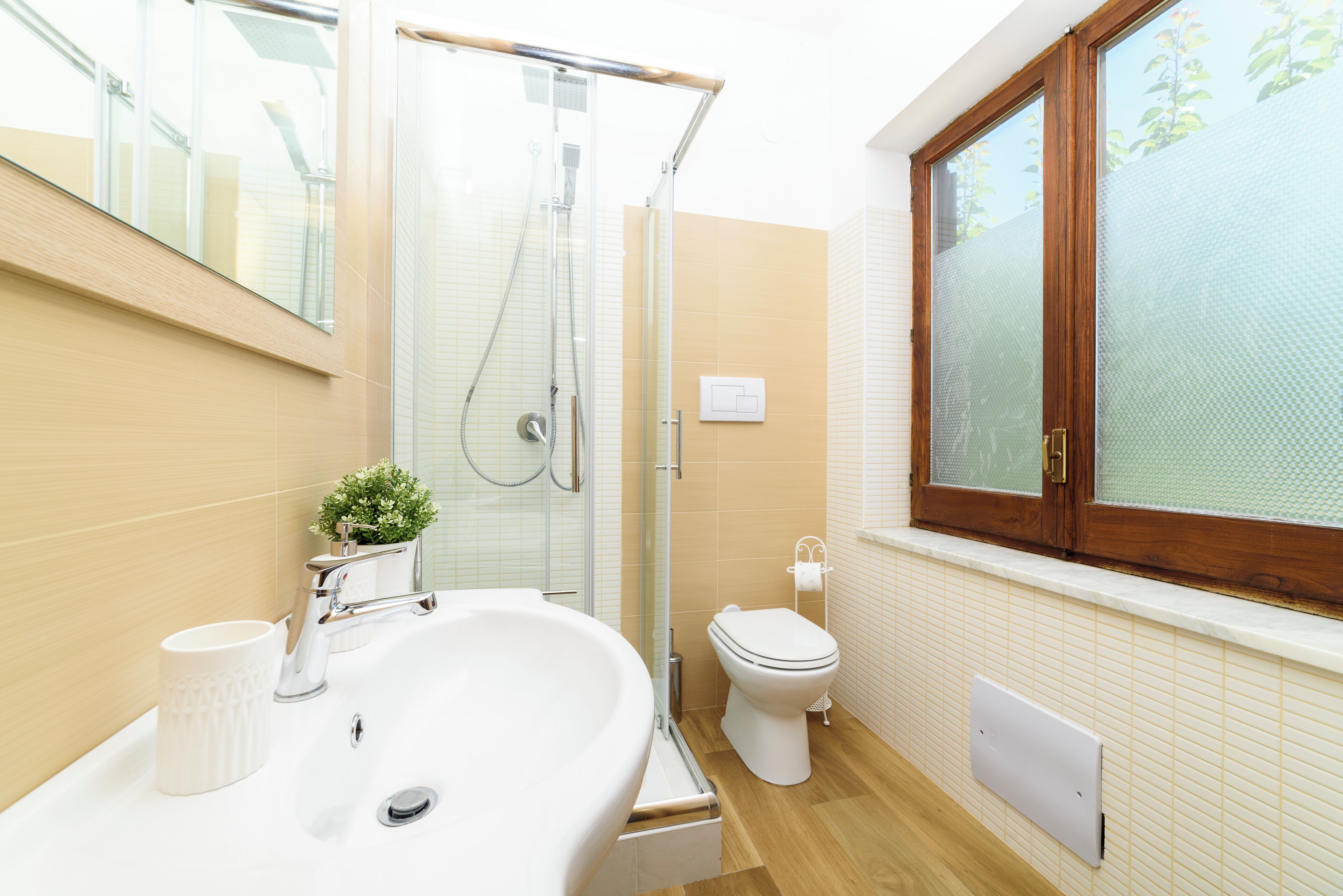 Un bagno moderno con cabina doccia in vetro, un lavandino bianco e un water.