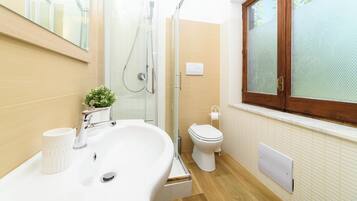 Un bagno moderno con cabina doccia in vetro, un lavandino bianco e un water.